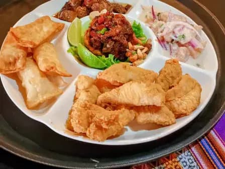 Tablita con tequeños, chicharrón, ceviche y salteado en fuente dividida